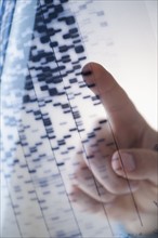 Human finger touching DNA chart.