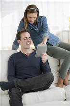 USA, New Jersey, Jersey City, Portrait of young couple sitting on sofa with digital tablet.