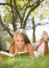 USA, New York, Girl (10-11) reading book in park. Photo : Jamie Grill Photography