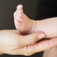 USA, New Jersey, Jersey City, Close-up view of mother's hand holding baby daughter leg (2-5 months)