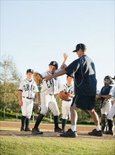 Baseball coach and boys (10-11) standing on baseball diamond.