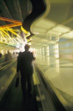 USA, Colorado, Businessman walking through airport, blurred motion. Photo : John Kelly