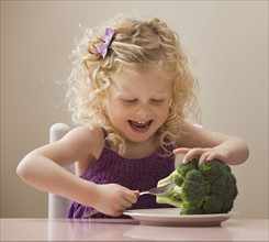 USA, Utah, Lehi, girl (2-3) eating broccoli. Photo : Mike Kemp
