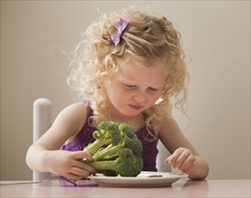 USA, Utah, Lehi, girl (2-3) eating broccoli. Photo : Mike Kemp
