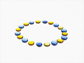 Studio shot of blue and yellow glass beads in circle. Photo : David Arky