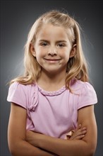 Portrait of girl (8-9) looking at camera with arms crossed, studio shot. Photo : FBP