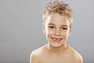 Studio portrait of toothless boy (8-9) smiling. Photo : FBP