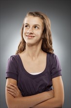 Portrait of girl (12-13) looking at camera with arms crossed, studio shot. Photo : FBP