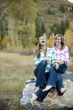 USA, Utah, Sundance, Two young women sitting on boulder and laughing. Photo : FBP