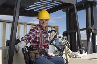 Portrait of female construction worker driving mechanical digger. Photo : Dan Bannister