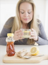 USA, New Jersey, Jersey City, Young woman drinking tea with ginger and lemon. Photo : Jamie Grill