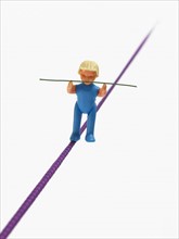 Studio shot of figurine balancing on tightrope. Photo : David Arky