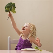 USA, Utah, Lehi, girl (2-3) holding broccoli. Photo : Mike Kemp