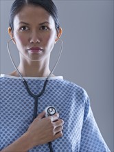 Female patient holding stethoscope to chest.