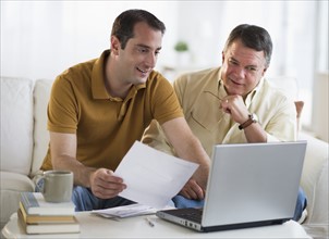 USA, New Jersey, Jersey City, Father and son using laptop in living room.