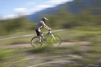 Canada, British Columbia, Fernie, Young man riding on mountain bike. Photo : Dan Bannister
