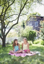 USA, New York, Two girls (10-11, 10-11) sitting on blanket in backyard. Photo : Jamie Grill