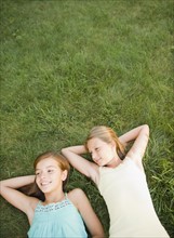 USA, New York, Two girls (10-11, 10-11) lying on grass backyard. Photo : Jamie Grill Photography