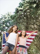 USA, New York, Two girls (10-11, 10-11) playing with American flag. Photo : Jamie Grill Photography