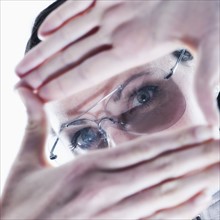 Portrait of young woman making finger frame over glasses.