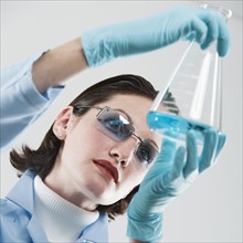 Female scientist examining chemical flask.