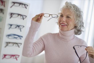 USA, New Jersey, Jersey City, Portrait of senior woman holding glasses.