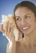 USA, New Jersey, Jersey City, Woman listening to conch shell.