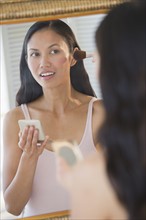 USA, New Jersey, Jersey City, Woman applying makeup in mirror.