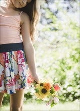 USA, New York, Girl (10-11) standing with bouquet of wildflowers. Photo : Jamie Grill Photography