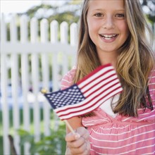USA, New York, Girl (10-11) holding American flag. Photo : Jamie Grill Photography