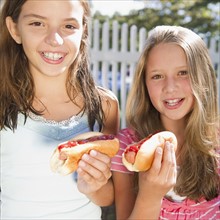 USA, New York, Two girls (10-11, 10-11) eating hot-dogs. Photo : Jamie Grill Photography