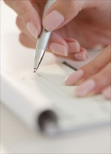 USA, New Jersey, Jersey City, Close-up view of woman's hand writing with pen. Photo : Jamie Grill