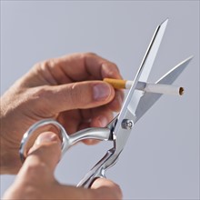 Hands cutting cigarette with scissors. Photo : Daniel Grill