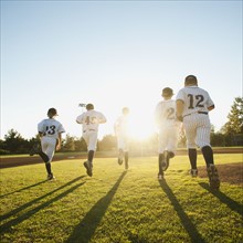 Baseball players (10-11) running on baseball diamond.