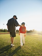 USA, California, Ladera Ranch, man and boy (10-11) walking on baseball field.