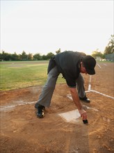 USA, California, Ladera Ranch, man drawing in sand on baseball diamond.