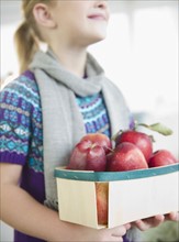 USA, New Jersey, Jersey City, Girl (8-9) holding box of apples. Photo : Jamie Grill Photography