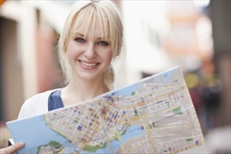 USA, Seattle, Smiling young woman holding map. Photo : Take A Pix Media