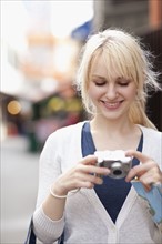 USA, Seattle, Smiling young woman holding digital camera. Photo : Take A Pix Media