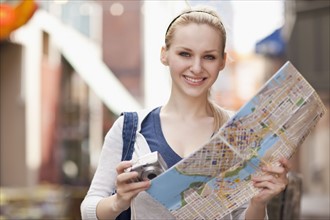 USA, Seattle, Smiling young woman holding map. Photo : Take A Pix Media