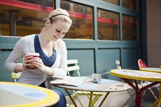 USA, Seattle, Young woman sitting with coffee and reading map. Photo : Take A Pix Media
