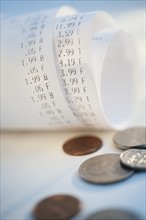Coins by rolled up receipts with prices.