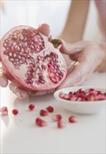 USA, New Jersey, Jersey City, Womans hand with pomegranate cross-section. Photo : Jamie Grill