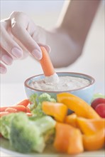USA, New Jersey, Jersey City, Close-up view of woman hand putting baby carrot into dip. Photo :
