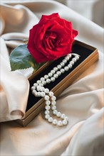 Rose with pearl necklace on satin material.