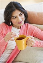 USA, New Jersey, Jersey City, Young attractive woman drinking tea from yellow cup. Photo : Daniel