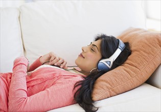 USA, New Jersey, Jersey City, Young attractive woman laying on back listening to music. Photo :