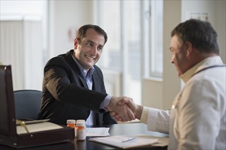 USA, New Jersey, Jersey City, Medical sales representative shaking hands with doctor in office.