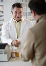 USA, New Jersey, Jersey City, Pharmacist selling medication in pharmacy.