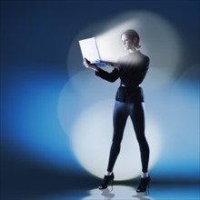 Young woman using laptop with bright light.